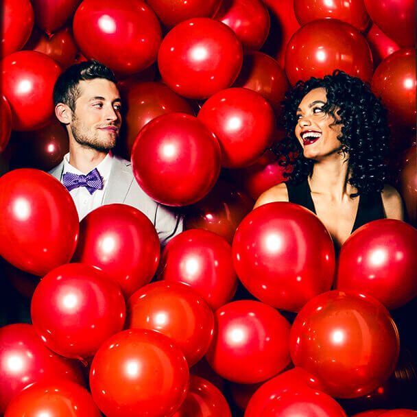 Couple standing in red balloons